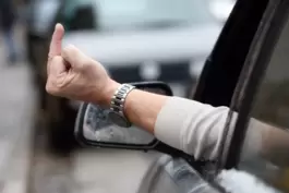 Eine Person zeigt einen Mittelfinger aus dem Autofenster