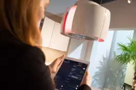 Eine Frau regelt die Küchenbeleuchtung mit einem Tablet