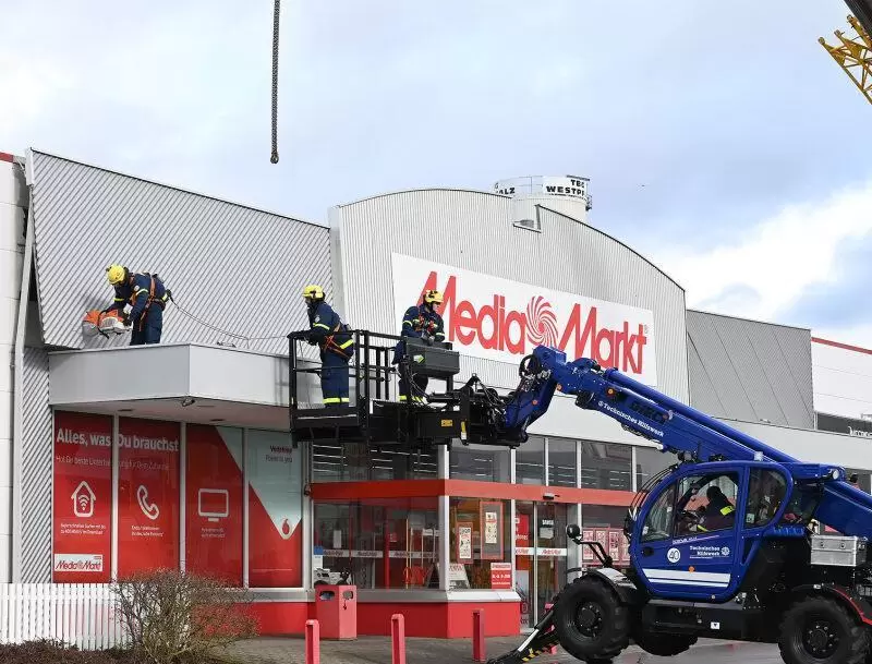 Das THW zerschneidet die Metallblende am Media Markt, bevor sie weg fliegen kann.