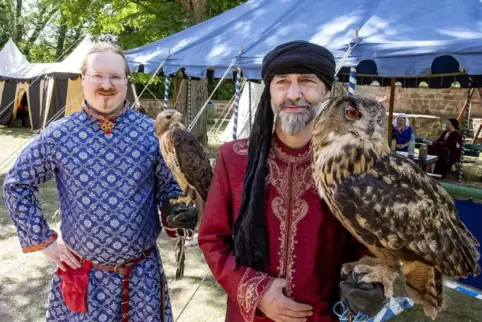 Mittelalterlich gewandete Herren mit Vögeln: Daniel Eckl (links) mit dem Rotschwanzbussard Fee und Thomas von Strzemieczny mit d