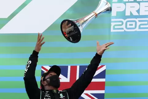 Lewis Hamilton lässt seine Trophäe fliegen. 
