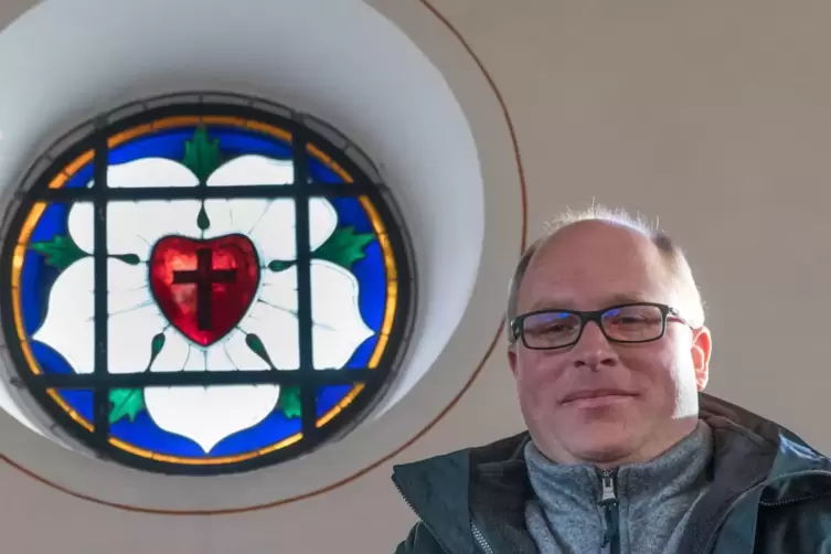 Pfarrer Christoph Bröcker vor der Lutherrose in der evangelischen Kirche Nandietschweiler. 