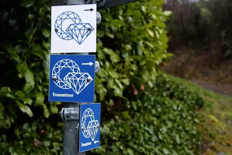 Die Wegweiser der Traumtour hängen bereits. Kennzeichen: Weißee Edelsteiner auf blaumen Grund. Oben hängt ein Schild des Diamant