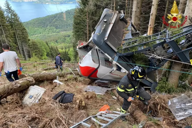 Rettungshelfer arbeiten am Wrack der abgestürzten Seilbahngondel.