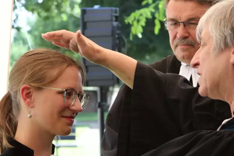 Dekanin Sieglinde Ganz-Walther segnet Pfarrerin Franziska Boltenhagen. Im Hintergrund: Pfarrer Ralf Hettmannsperger.