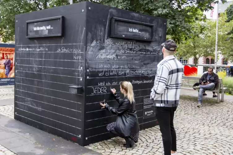  Nadine Heil schreibt hier gerade ihre Gedanken an den Courage-Kubus, dahinter steht Felix Jülg.