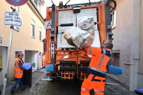 Mit Schwung: Lader Patrick Rupp wirft Müllsäcke ins Fahrzeug, Irmgard Münch-Weinmann karrt eine Papiertonne heran.