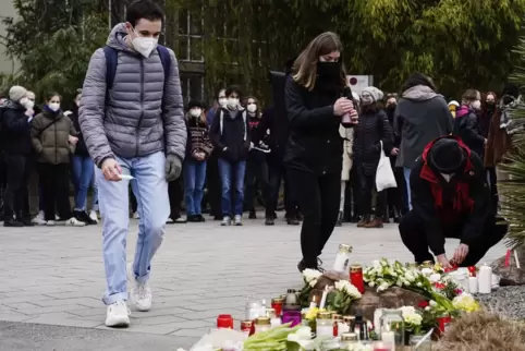 Am Dienstag haben Menschen vor einem Gebäude der Universität Blumen und Kerzen an den Wegesrand gelegt. 