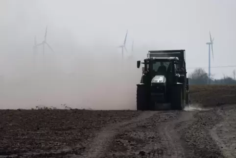 Ein Traktor wirbelt auf einem trockenen Feld viel Staub auf.