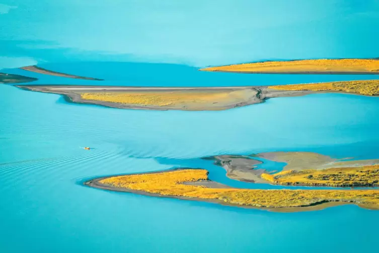 Wildnis in Schwedisch-Lappland: zerklüftete Landschaft und ein pastellblauer Gletscherfluss im Sonnenlicht.