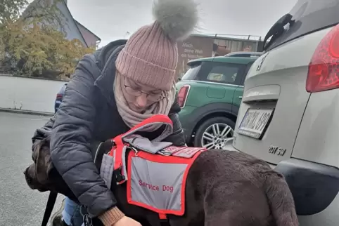 Lena Kliegl macht ihren Assistenzhund „Happy“ einkaufsfertig, in dem sie ihm die Weste anlegt. Diese weist ihn als Begleithund a