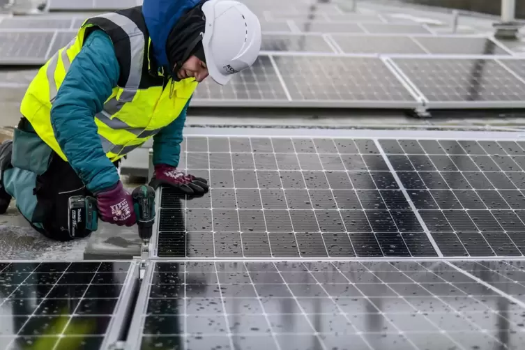 Ein Arbeiter montiert Solarmodule. 