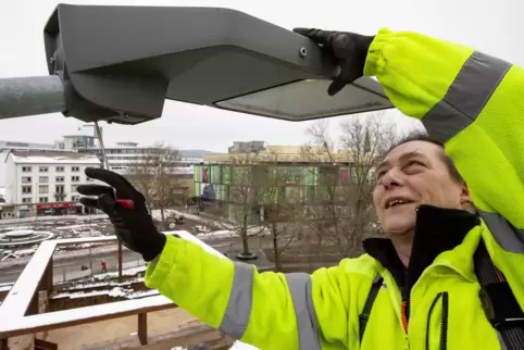 Elektroinstallateur Uwe Fischer bei Wartungsarbeiten an einer Straßenlaterne vor dem Rathaus.