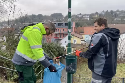 Sascha Gries (links) hält die Tüte, während Jens Schmeltzle den Mülleimer auf dem Parkplatz am Horst-Eckel-Haus ausräumt. 