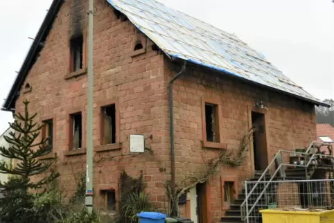 Eine Plastikplane auf dem Dach schützt das vom Feuer zerstörte Haus. 