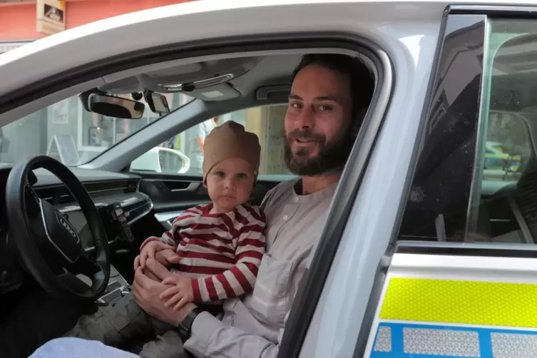 Jakob sitzt mit Papa Jens Benda im Streifenwagen. 