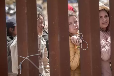 Junge Frauen aus süd- und mittelamerikanischen Staaten stehen in Tijuana hinter dem Grenzzaun, der Mexiko von den USA trennt. 