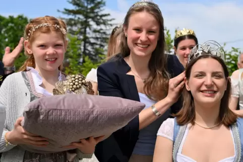 Die pfälzische Weinprinzessin Sandra Eder setzt Emma Klemm die neue Krone auf. Daneben die Traubenblütenprinzessin Leni Dörlich 