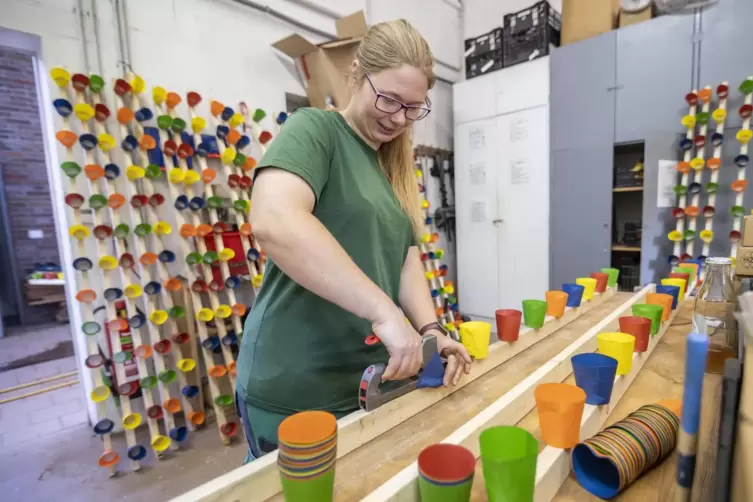 Gärtnerin Ina Kipp tackert in der Rosengarten-Werkstatt bunte Papierbecher auf 100 Dachlatten. 