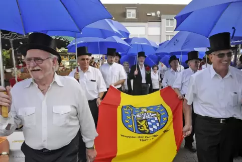 Die Kerweborsch mit der Ortsfahne auf dem Weg zum Kerweplatz. 