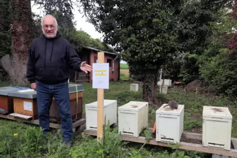 Imker Rüdiger Muckel auf seinem gepachteten Gelände, wo er Bienenkästen stehen hat; er deutet auf ein Schild, was darauf hinweis