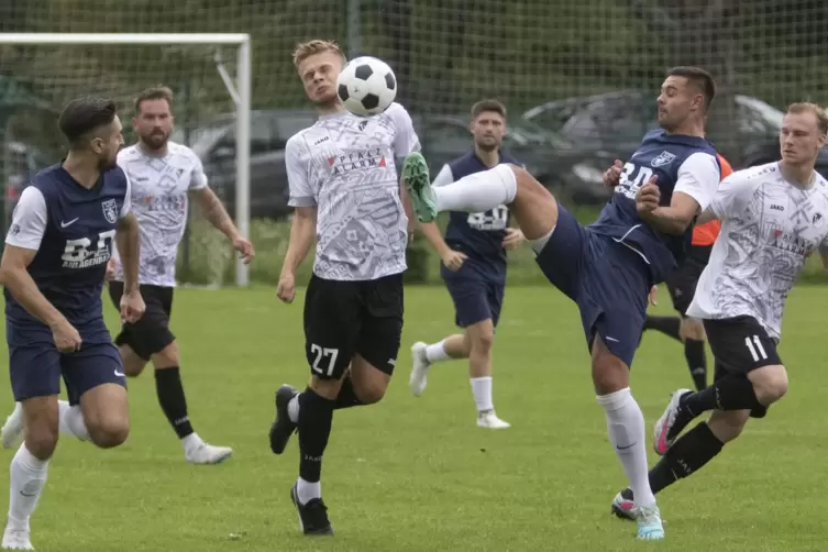 Jannik Scheller (FV Ramstein) versucht mit dem Fuß an den Ball zu kommen. In der Mitte Max Lukas vom TuS Steinbach. 