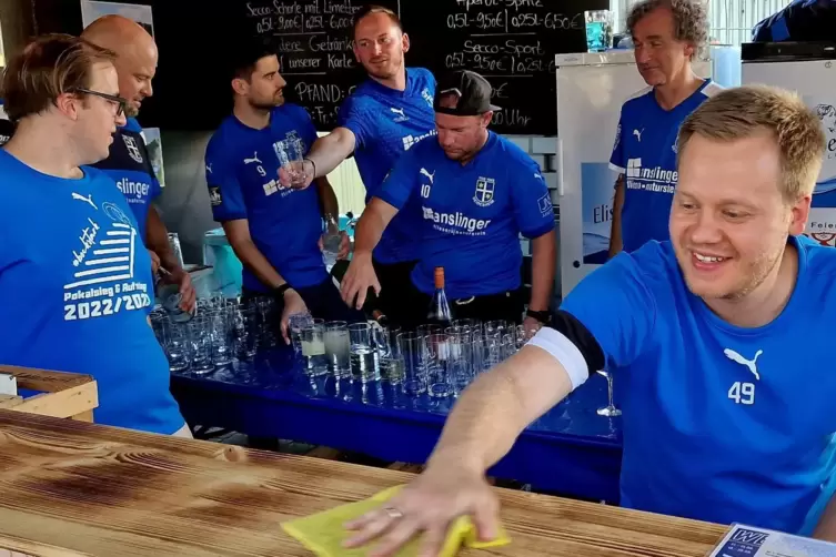 Jonas Rieger wischt die Theke (rechts), während seine TSG-Kollegen Weinschorle vorbereiten.