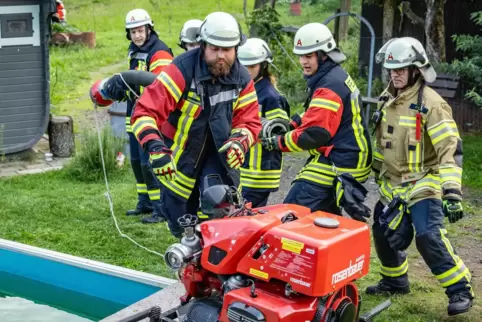 Aus dem Löschteich am Heidehof werden Schläuche zur Brandbekämpfung verlegt.