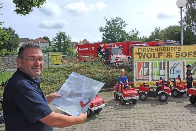 Feuerwehr- und Katastrophenschutzinspekteur Frank Theisinger zeigt den Bauplan für die neue Halle, die in Richtung Bahneinschnit