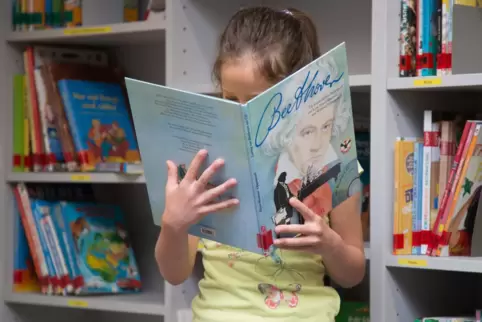 Ein Kind liest in einer Bücherei (Symbolbild).