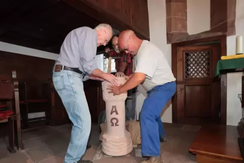 Wuchten den Taufstein an seinen Platz (von links): Peter Scheifling, Bildhauer Bruno Weygand und Hans Bickel. 