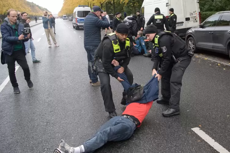 Polizeibeamte ziehen eine Umwelt-Aktivistin von der Straße des 17. Juni. 