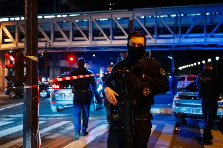 Frankreich, Paris: Ein Polizeibeamter steht am Tatort Wache. 