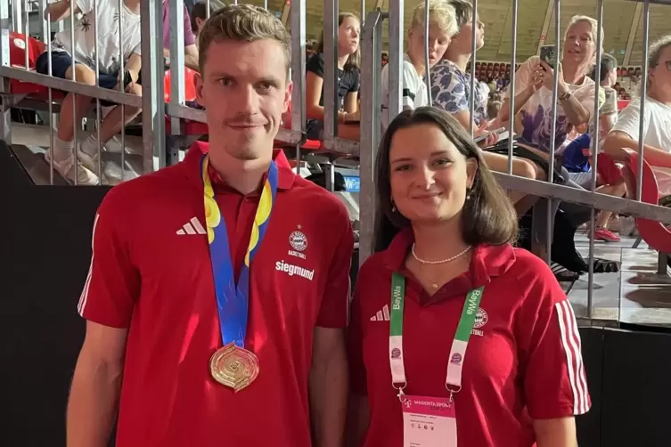 Emma Bauer neben Basketball-Weltmeister Andreas Obst (FC Bayern München) mit seiner Goldmedaille von der WM 2023.