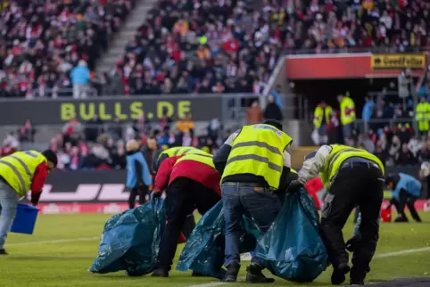 Ordner sammeln Schokotaler auf, die Fans beim Bundesliga-Spiel 1. FC Köln - Borussia Dortmund aus Protest gegen die Investorenpl