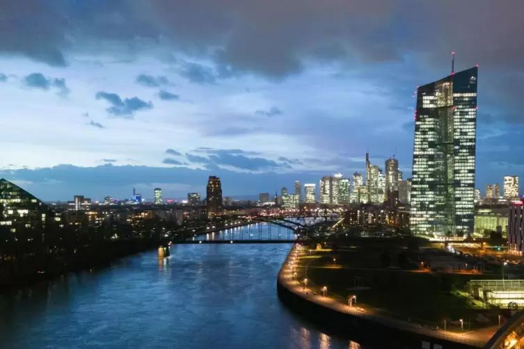 Die EZB leuchtet vor der Hochhauskulisse der Innenstadt von Frankfurt am Main. 