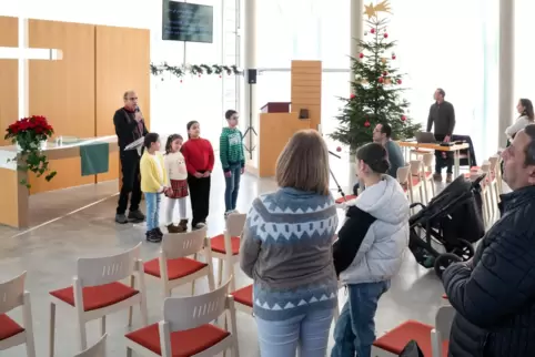 Arabischer Gottesdienst im Speyerer Süden: Raouf Emad liest einen Psalm, die Kinder sind bei ihm im Altarraum.