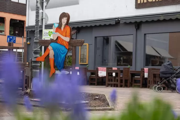 Die Kaffee trinkende Frau fällt direkt wegen ihrer farbenfrohen Kleidung auf. Sie sitzt in der St.-Michael-Straße vor dem Restau