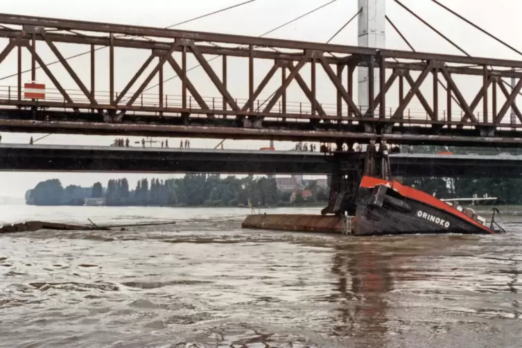 Die „Orinoko“ hängt am Brückenpfeiler. Auf der Straßenbrücke beobachten Schaulustige das Geschehen. 