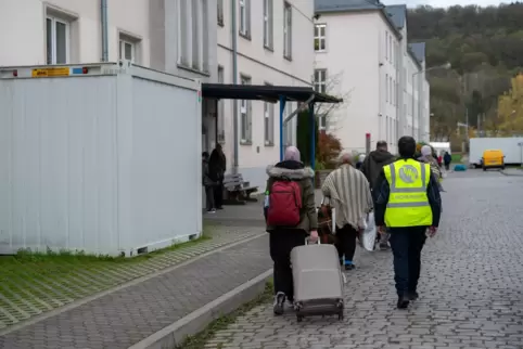 Streitpunkt Migrationspolitik: Neuangekomme Flüchtlinge gehen mit ihren Koffern in eines der Wohnhäuser der Aufnahmeeinrichtung 