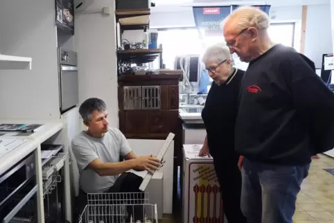 Stefan Schneider bereitet eine Spülmaschine für die Auslieferung vor, rechts daneben Doris und Klaus Schneider. An eine Gaststät