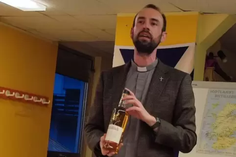 Pfarrer Tobias Heil präsentiert einen von fünf Single Malt Whiskys, die verkostet wurden. 
