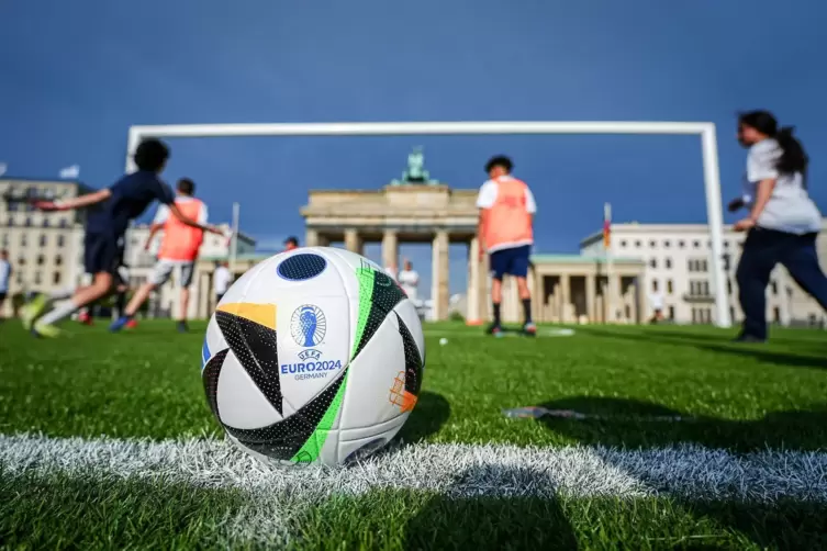 Kinder spielen in Berlin auf dem Kunstrasen vor dem Brandenburger Tor mit dem riesigen Fußballtor hinter dem offiziellen Ball fü