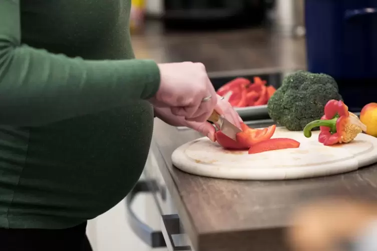 Eine schwangere Frau schneidet Gemüse