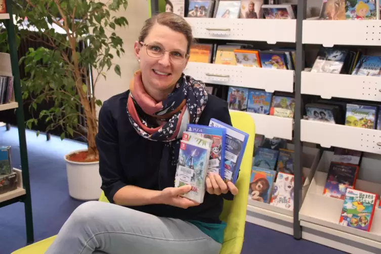 Marie-Luise Selzer mit einer Auswahl an Konsolenspielen in der Bücherei in Eisenberg.