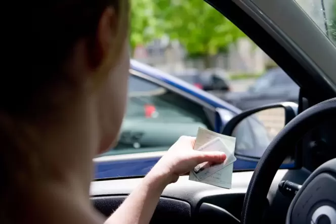 Eine Frau hält Fahrzeugpapiere in der Hand