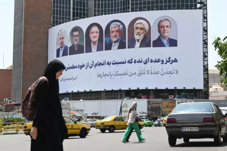 Eine Frau in Teheran vor einem Plakat mit den iranischen Präsidentschaftskandidaten. 