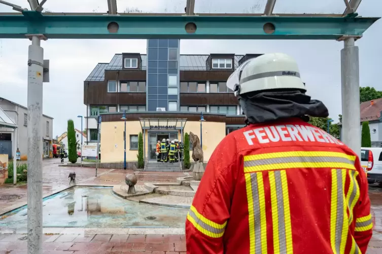 Ein Feuerwehrmann vor dem Rathaus in Dudenhofen: Von außen ist kein Schaden zu sehen.
