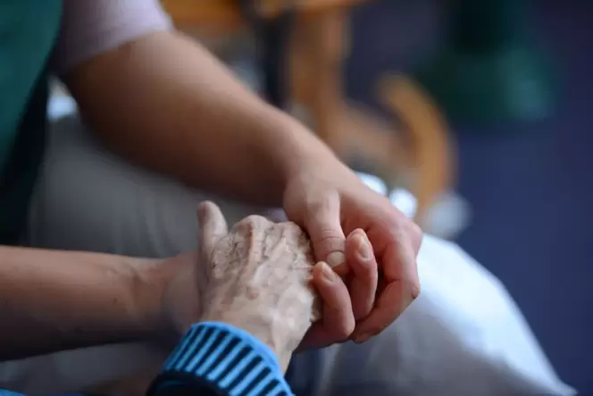 Eine Frau hält die Hand einer Seniorin