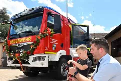 Feuerwehrmann André Briglia zeigt Besucher Leon die Ausrüstung des neuen Feuerwehr-Fahrzeugs.